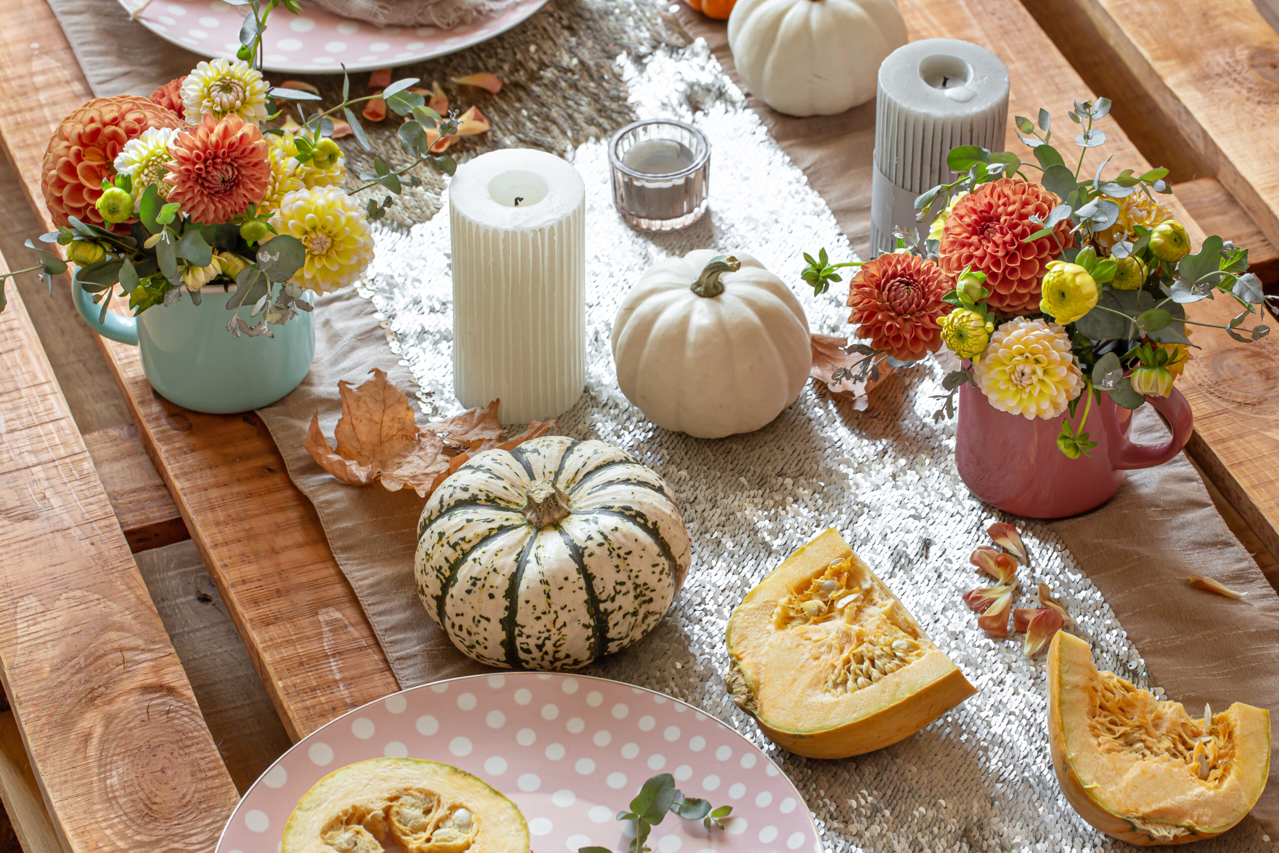 Festive table setting with pumpkins, candles and chrysanthemum flowers.